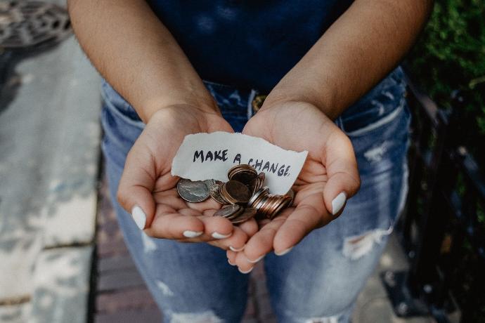 Kvinna som håller pengar och en lapp där det står Make a change